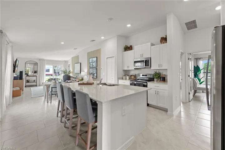 Kitchen featuring stainless steel appliances, open floor plan, recessed lighting, white cabinets, and a breakfast bar