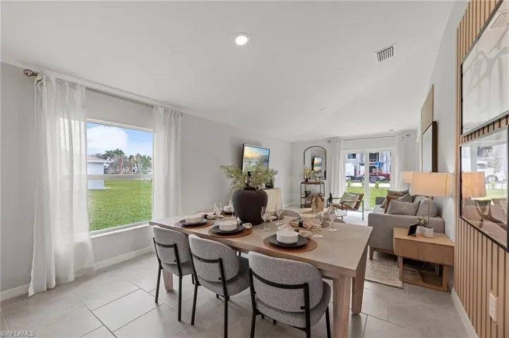 Dining area featuring healthy amount of natural light, light tile patterned floors, vaulted ceiling, and recessed lighting