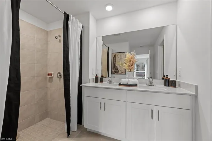 Full bathroom featuring a shower stall, double vanity, and light tile patterned flooring