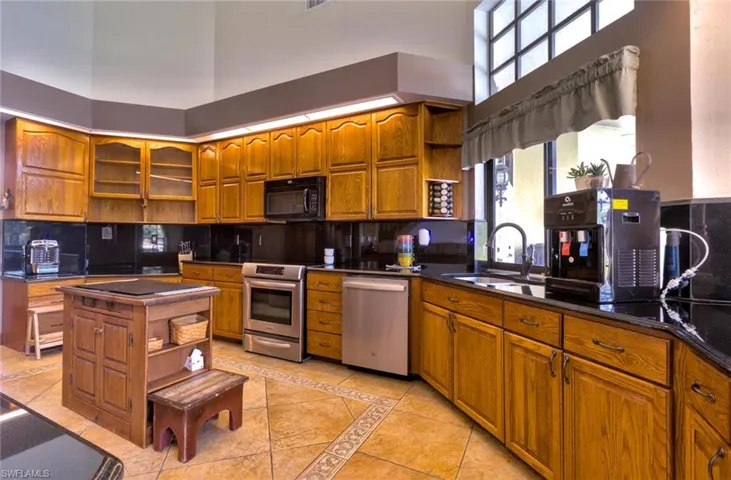 Kitchen featuring light tile flooring, stainless steel appliances, high end granite, and elegant backsplash
