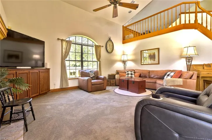 Family room with soaring vaulted ceiling, carpet, and ceiling fan