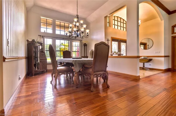 Formal dining room with wood flooring, high ceilings, and inviting chandelier
