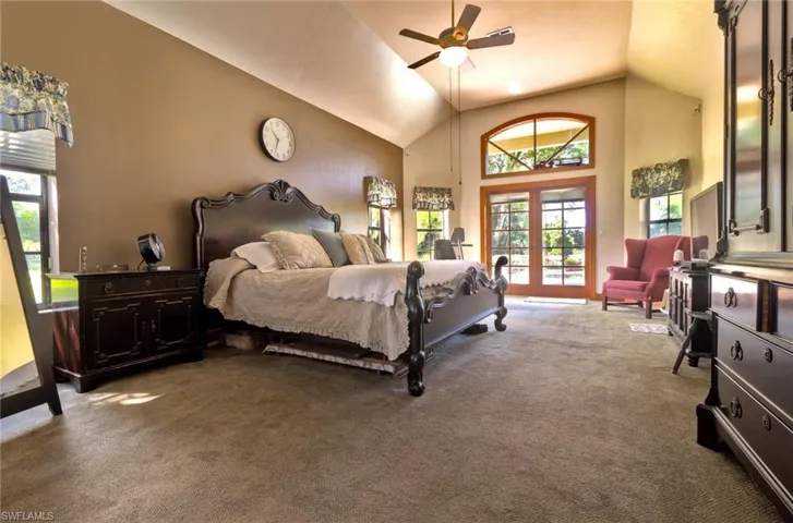 Master Bedroom with high vaulted ceiling, ceiling fan, french doors for serene views of lush green acreage, native trees and flowering bushes