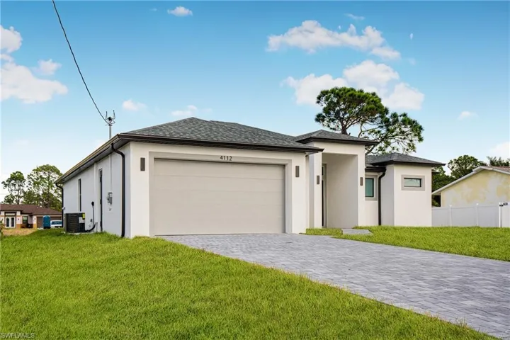 Prairie-style home featuring stucco siding, an attached garage, and decorative driveway