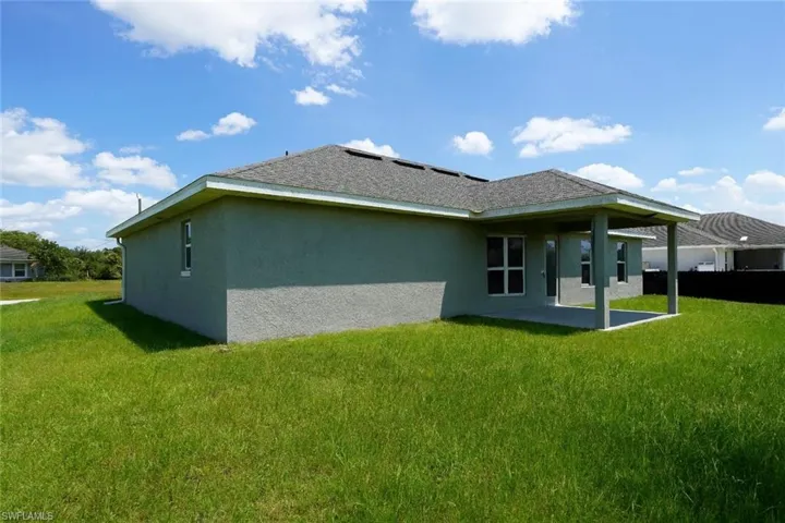 Back of property featuring a lawn, a patio, and stucco siding