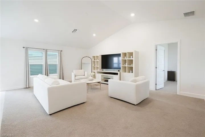 Living room featuring recessed lighting, light carpet, and high vaulted ceiling