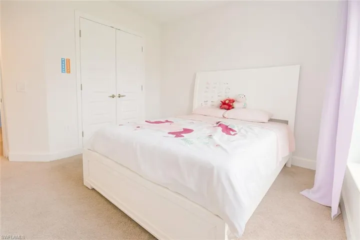 Bedroom featuring light carpet and a closet