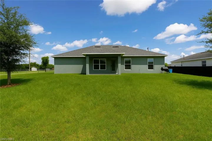 Rear view of house featuring a patio area, stucco siding, and a shingled roof