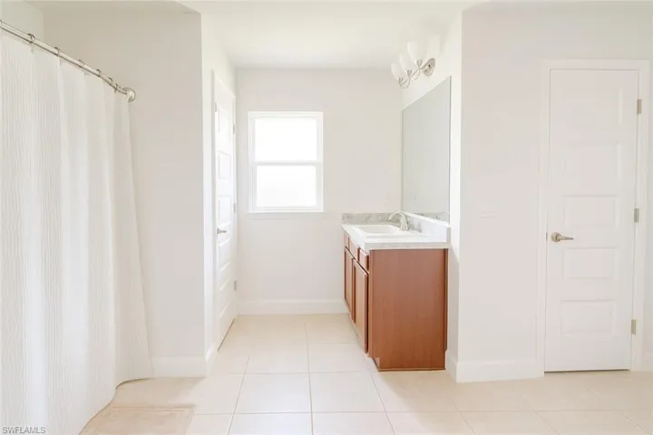 Full bathroom with vanity, a shower with curtain, and light tile patterned floors