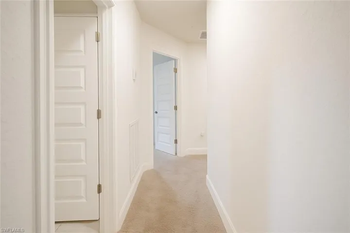 Corridor with light carpet and baseboards