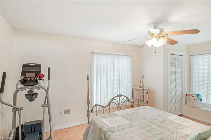 Tiled bedroom featuring a closet, multiple windows, and ceiling fan