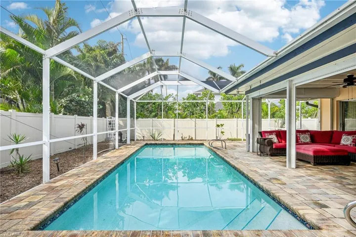 View of pool featuring a patio, glass enclosure, and an outdoor hangout area