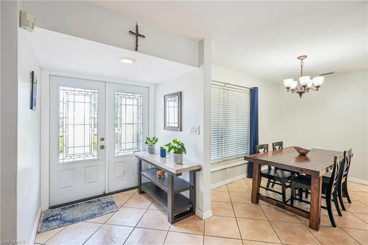 Entrance foyer with light tile patterned floors and a notable chandelier