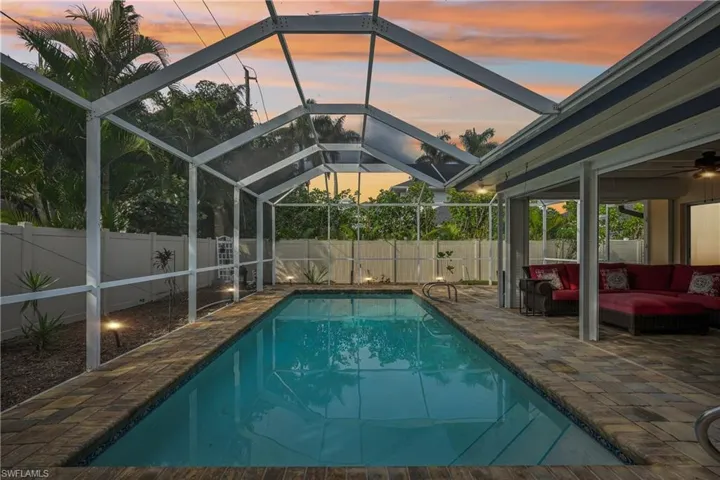 Pool at dusk with an outdoor living space, a lanai, and a patio