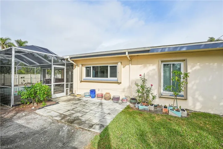 Back of house with a lawn, a patio area, and a lanai