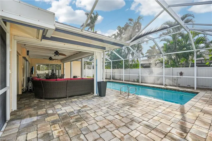 View of swimming pool with glass enclosure, an outdoor living space, ceiling fan, and a patio