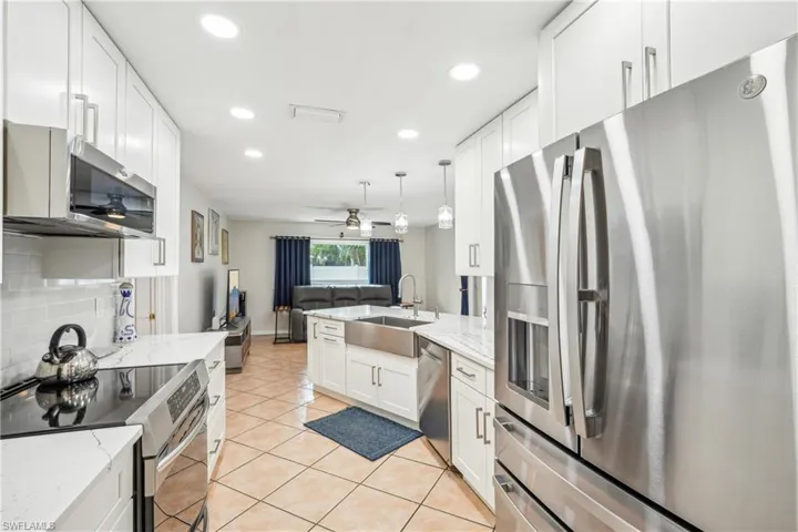 Kitchen with white cabinets, hanging light fixtures, sink, and appliances with stainless steel finishes