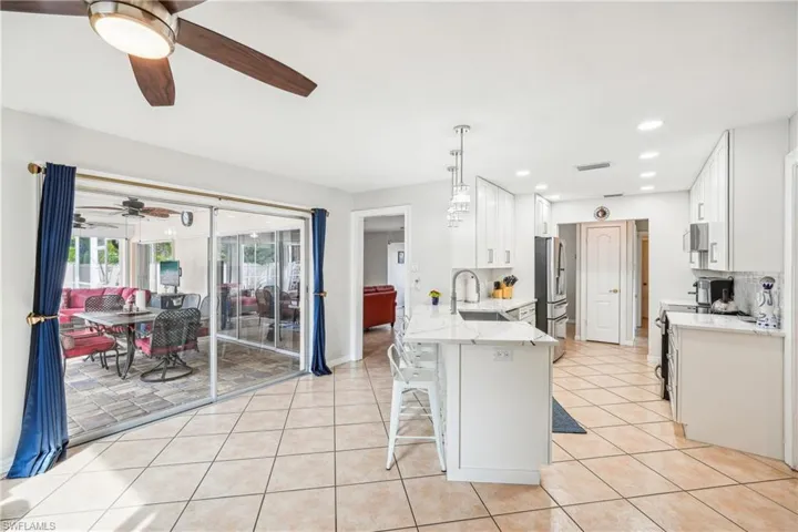 Kitchen with kitchen peninsula, decorative light fixtures, a breakfast bar area, white cabinets, and appliances with stainless steel finishes
