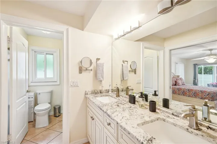 Bathroom featuring toilet, vanity, tile patterned floors, and a wealth of natural light