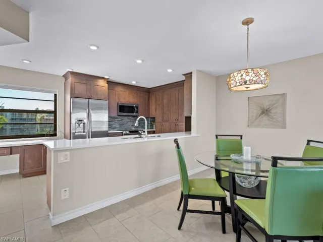 Kitchen featuring decorative backsplash, appliances with stainless steel finishes, sink, light tile patterned floors, and hanging light fixtures