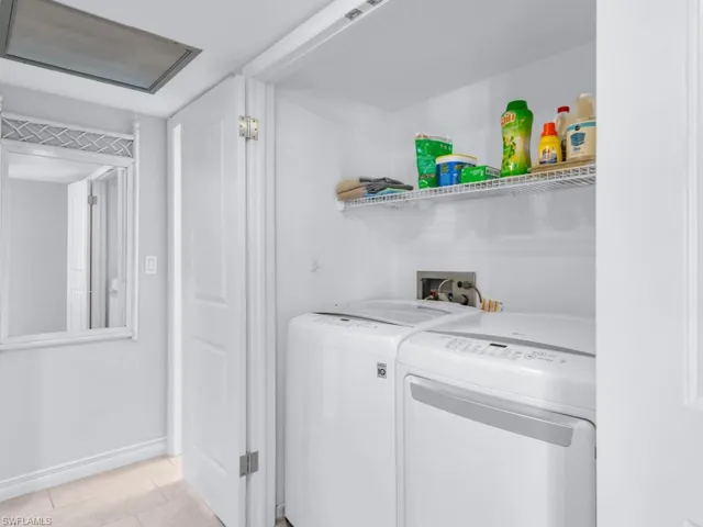 Clothes washing area with light tile patterned flooring and independent washer and dryer