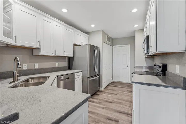 Kitchen featuring white cabinetry, sink, quartz countertops, SS appliances with stainless steel finishes, and LVP  flooring