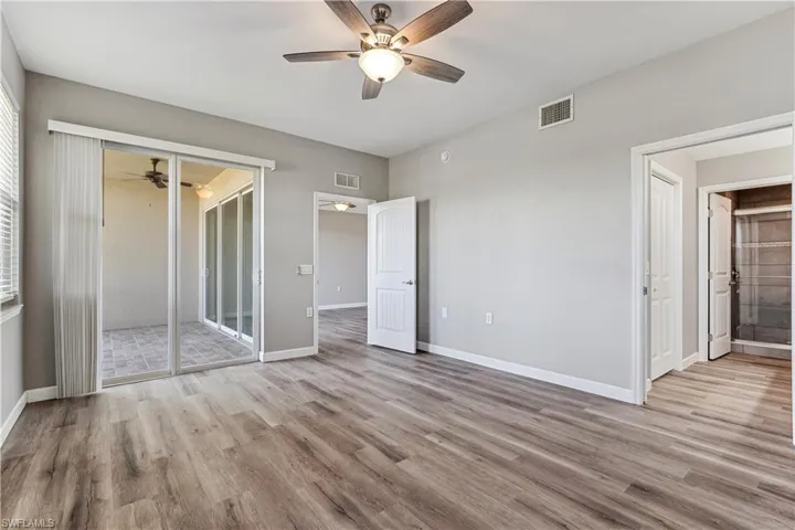 Unfurnished bedroom with LVP flooring, connected bathroom, access to outside, and ceiling fan