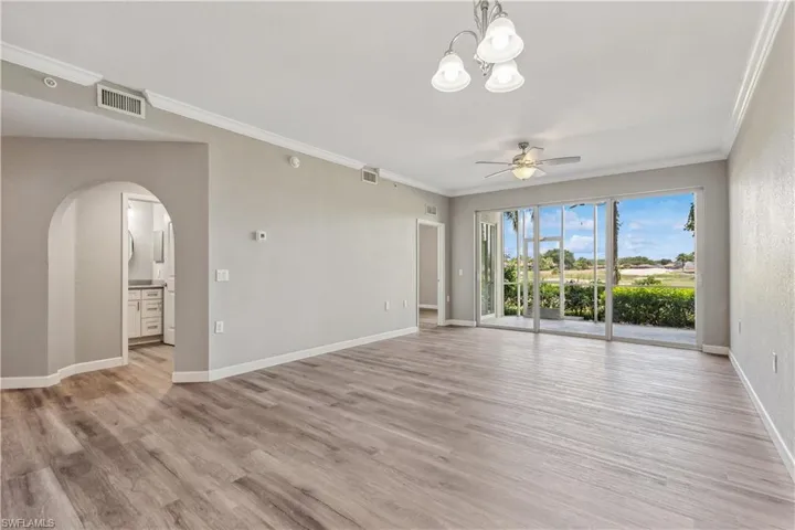 Unfurnished living room featuring crown molding, ceiling fan with notable chandelier, and LVP style flooring