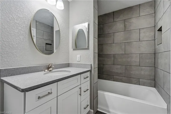 Bathroom featuring tiled shower / bath combo, vanity, and a textured ceiling
