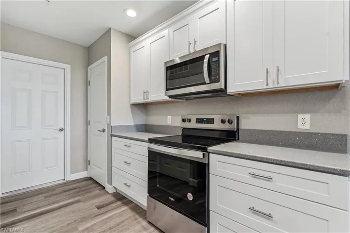 Kitchen with SS appliances, LVP floors, and white cabinetry with quartz countertops
