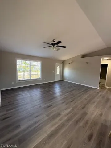 Kitchen with ceiling fan, white appliances, white cabinets, vaulted ceiling, and a kitchen island