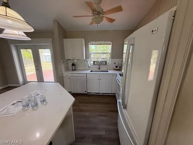 Kitchen with stove, white fridge with ice dispenser, a sink, lofted ceiling, and white cabinets