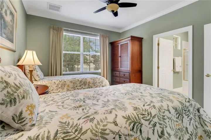 Bedroom with ceiling fan, ensuite bath, and crown molding
