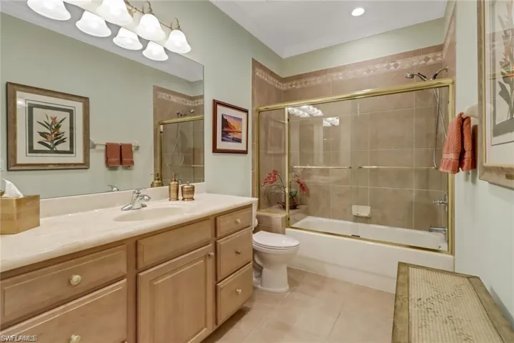 Full bathroom with tile patterned floors, vanity, shower / bath combination with glass door, and toilet
