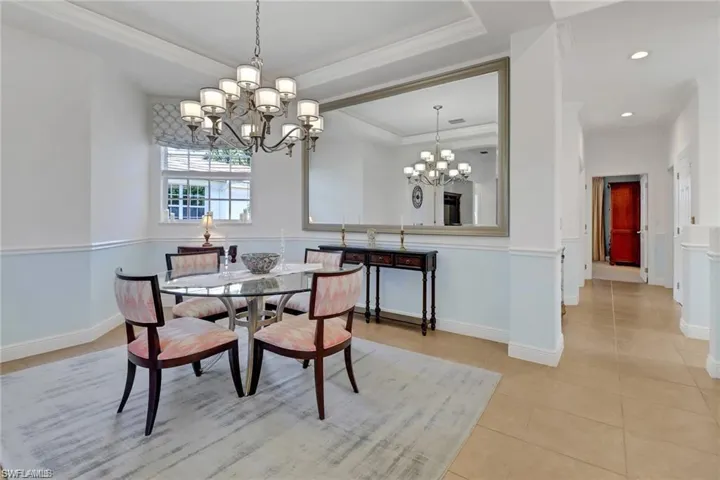 Dining area featuring a raised ceiling, an inviting chandelier, and light tile patterned floors