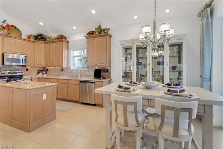 Kitchen with stainless steel appliances, decorative backsplash, sink, light tile patterned floors, and a kitchen island
