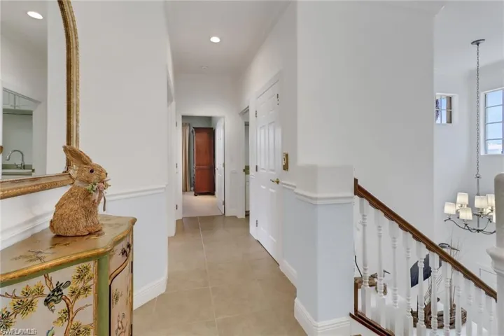 Hallway featuring sink, ornamental molding, a chandelier, and light tile patterned floors