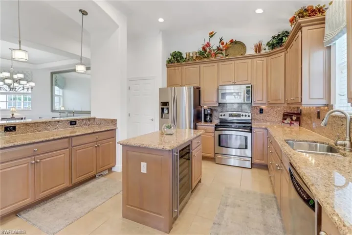 Kitchen featuring sink, appliances with stainless steel finishes, light stone counters, tasteful backsplash, and a kitchen island