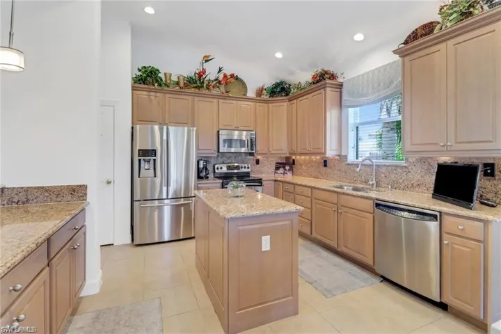 Kitchen featuring a kitchen island, light brown cabinetry, light tile patterned floors, and stainless steel appliances