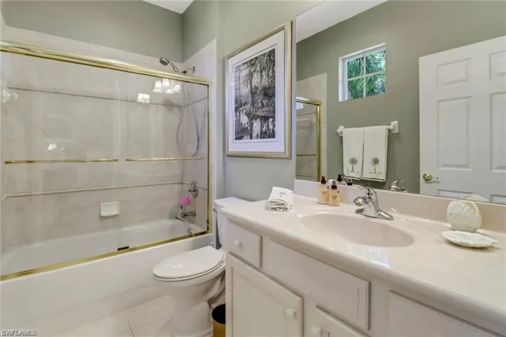 Full bathroom featuring tile patterned floors, vanity, combined bath / shower with glass door, and toilet