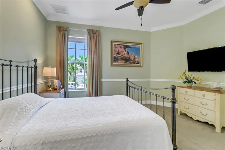 Bedroom with ceiling fan, carpet flooring, and crown molding