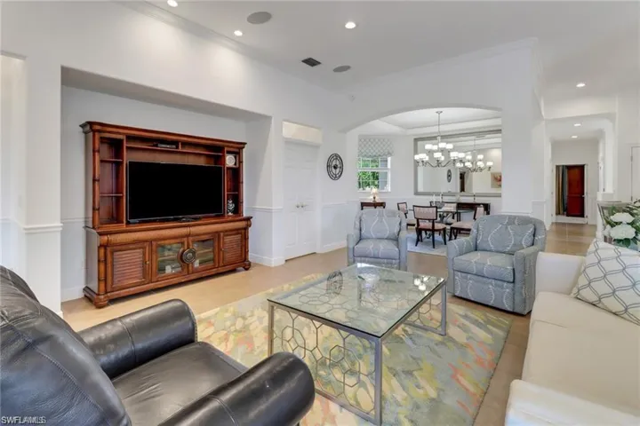 Tiled living room with a notable chandelier and ornamental molding