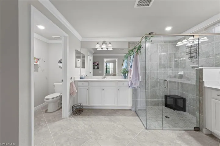 Primary Bathroom featuring dual vanities, a large walk in shower, recessed lighting and crown molding