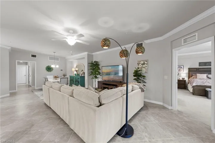 Living area with crown molding, ceiling fan, and light tile patterned floors
