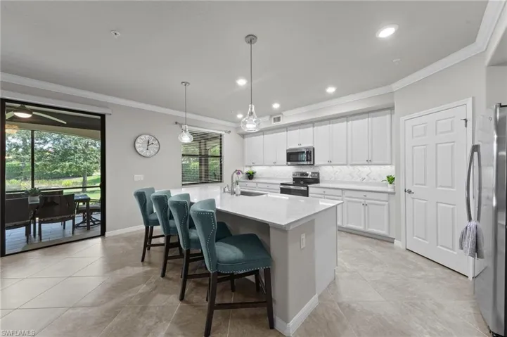 Kitchen featuring a large island, generous pantry, ample counter area,  beautiful custom backsplash, and decorative light fixtures