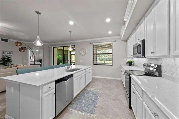 Kitchen featuring a large island, beautiful custom backsplash, stainless appliances, and decorative light fixtures