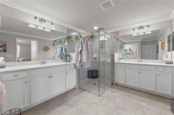 Primary Bathroom featuring dual vanities, a large walk in shower, recessed lighting and crown molding
