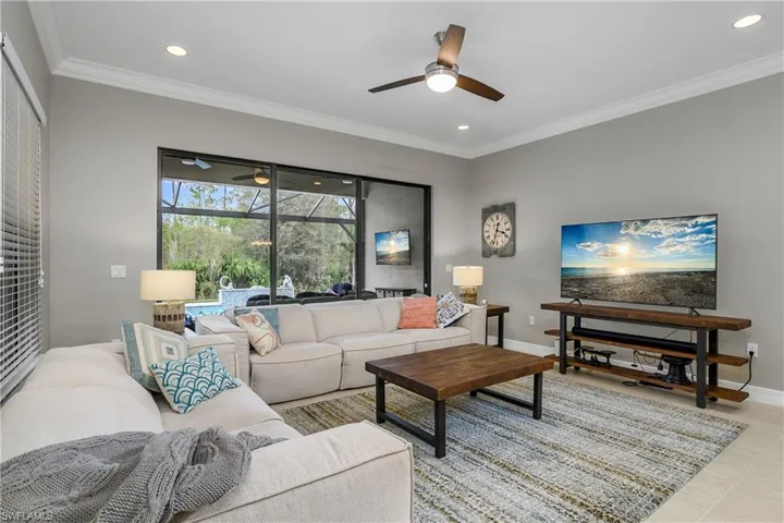 Living room featuring ornamental molding, light tile patterned flooring, and ceiling fan