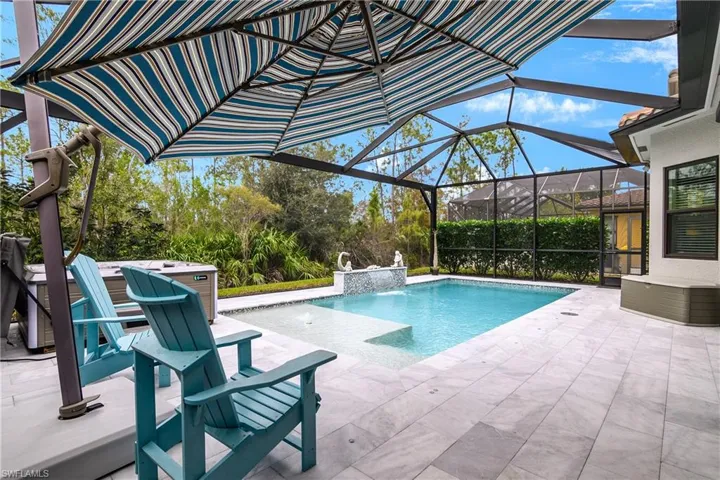 View of pool with a patio, glass enclosure, and pool water feature