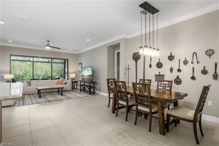 Tiled dining area with ceiling fan and ornamental molding